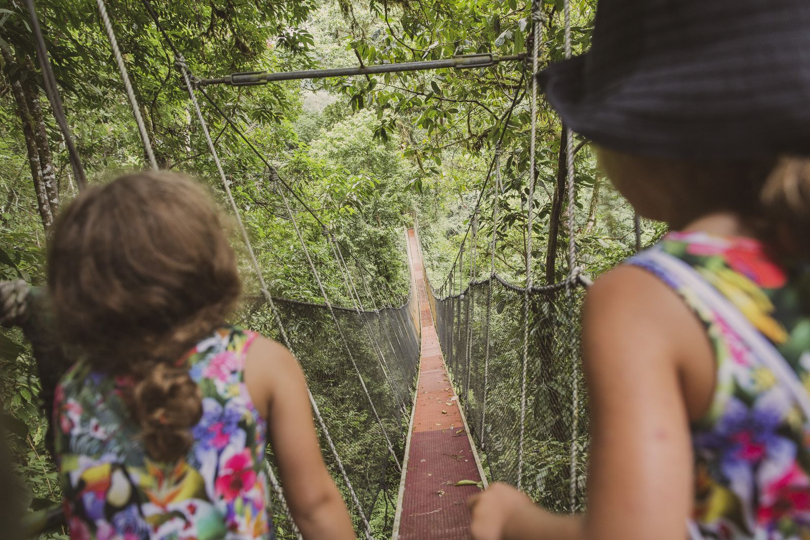 Two girls crossing a rope bridge in the rainforest